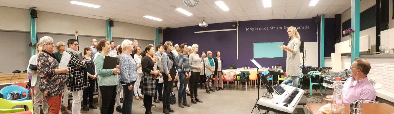 Erica begeleidt een zanggroep tijdens een workshop